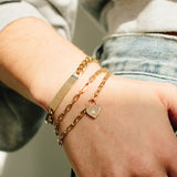 woman wearing Zoe Chicco 14kt Gold Star Set Diamond Heart Padlock Bracelet stacked with other heavy metal chain bracelets on her wrist