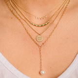 close up of Zoe Chicco 14kt gold amore XS curb chain necklace layered with a pearl lariat and gold and diamond necklaces