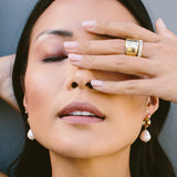 woman with one hand covering her eye wearing Zoë Chicco 14kt Gold Chubby Huggie Hoops with Dangling Baroque Pearls on her ears
