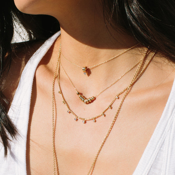 woman in white tank top wearing Zoë Chicco 14kt Gold Prong Diamond Rondelle Necklace layered with three other necklaces