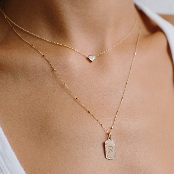 close up of woman wearing a Zoë Chicco 14kt Gold Tiny Bar and Cable Chain Necklace with a letter R Pave Diamond Border Dog Tag Pendant and  a one of a kind shield diamond necklace
