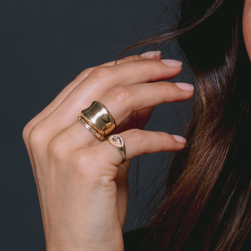 woman's hands wearing Zoë Chicco 14kt Gold Chunky Concave Ring on her ring finger stacked with a Baguette Diamond Eternity Band