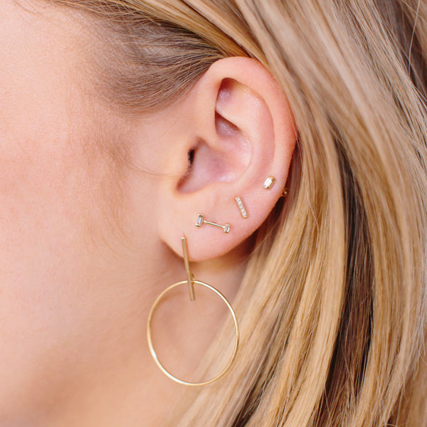 woman's ear wearing Zoë Chicco 14kt Gold Baguette Diamond Barbell Stud Earrings
