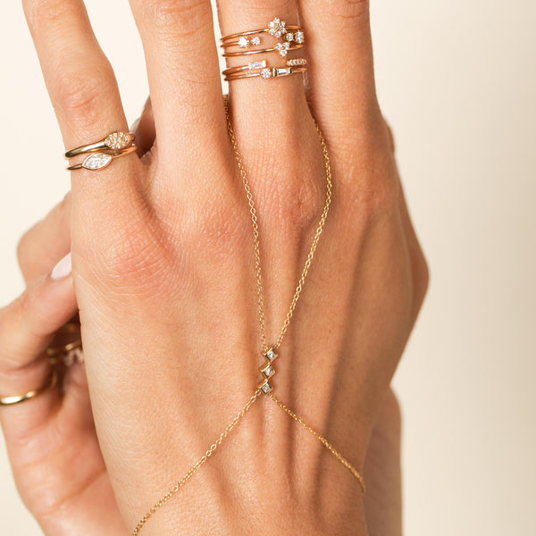 close up of woman's hand wearing a Zoe Chicco 14k Gold 3 Princess Diamond Hand Chain with rings stacked on her fingers