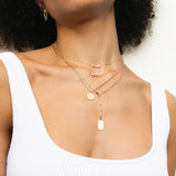 woman in white tank top wearing Zoë Chicco 14k Gold Medium Diamond Disc with Diamond Border Square Oval Chain Necklace layered with three other necklaces