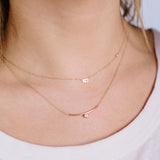 woman wearing Zoë Chicco 14kt Gold Curved Bar Necklace with Diamond Bezel layered with an XO floating diamond necklace