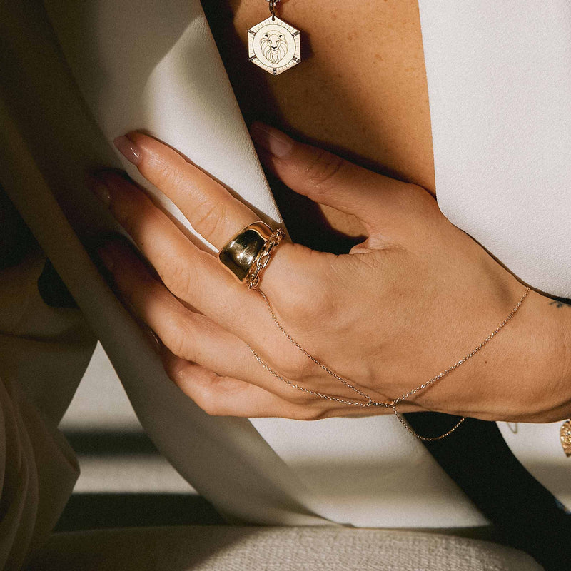 woman in white blazer wearing a Zoë Chicco 14k Gold Solid Large Square Oval Link Chain Ring layered with a Concave Chunky Band ring and wearing a hand chain