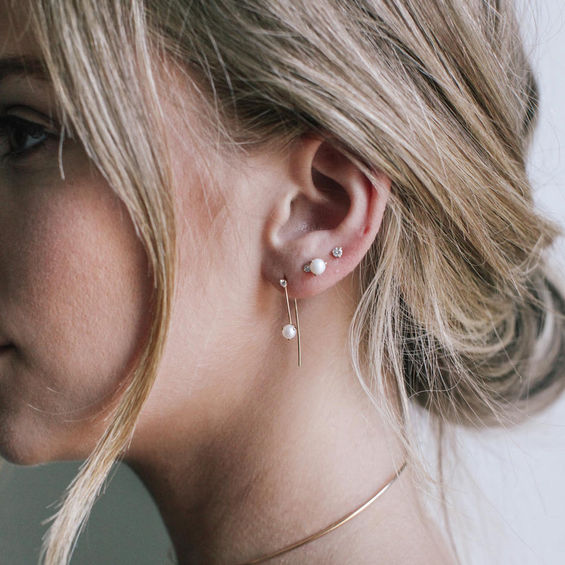 side profile of a woman wearing a Zoë Chicco 14k Gold Pearl & Diamond Wire Threader Earring layered with two pearl and diamond studs