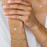 woman's wrist wearing Zoë Chicco 14kt Gold 14k Large Princess Diamond Bezel Bolo Bracelet stacked with other diamond bracelets