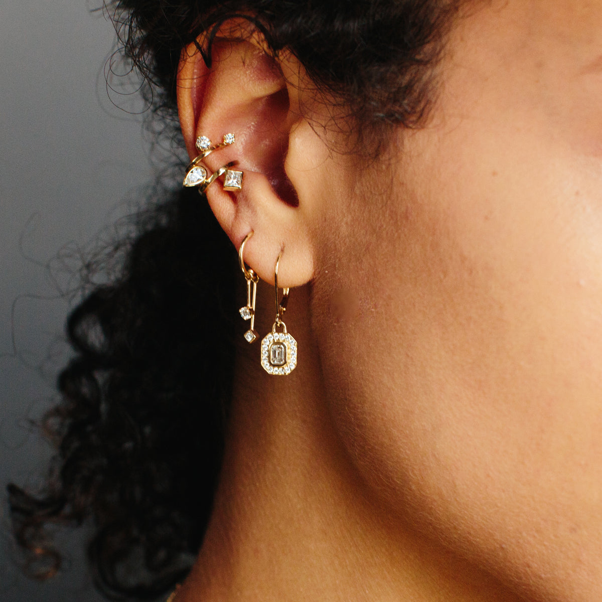 woman wearing multiple Zoe Chicco 14k gold and diamond earrings on a dark background