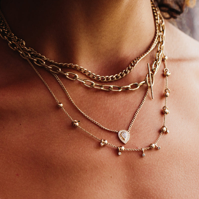 woman wearing a Zoë Chicco 14k Gold Medium Curb Chain Necklace layered with three other necklaces