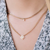 woman's neck wearing Zoë Chicco 14kt Gold Single Prong Diamond Small Curb Chain Necklace layered with a Princess Diamond Halo Curb Chain Necklace