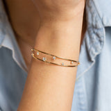 close up of woman's wrist wearing Zoë Chicco 14kt Gold Prong Diamond Double Band Cuff Bracelet