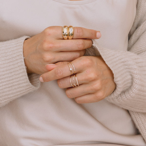 woman in a beige top and sweater wearing Zoë Chicco 14k Gold Triple Pavé Diamond Band Ring on her middle finger