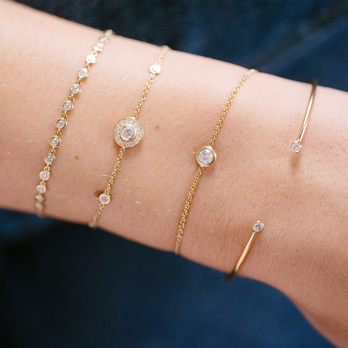 wrist wearing Zoe Chicco 14kt Gold Single Floating Diamond Bracelet stacked with other diamond bracelets