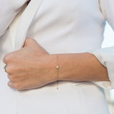 woman in white blazer wearing Zoe Chicco 14kt Gold Single Large Floating Diamond Bolo Bracelet on her wrist