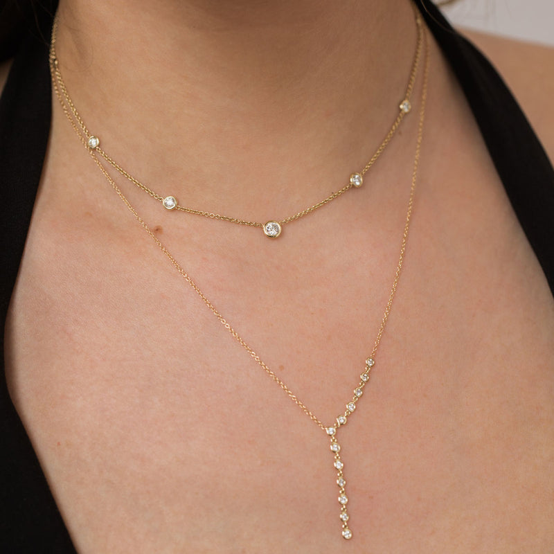 woman wearing Zoë Chicco 14kt Gold 12 Linked Floating Diamonds Lariat Necklace layered with a Graduated Floating Diamond Necklace