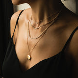 Woman in black camisole top wearing a Zoe Chicco 14k Gold Half Carat Floating Diamond Necklace layered with a Small Curb Chain Floating Diamond Necklace, Mixed Small and Medium Square Oval Link Chain Necklace, and a Star Set Diamond Round Locket Pendant Necklace