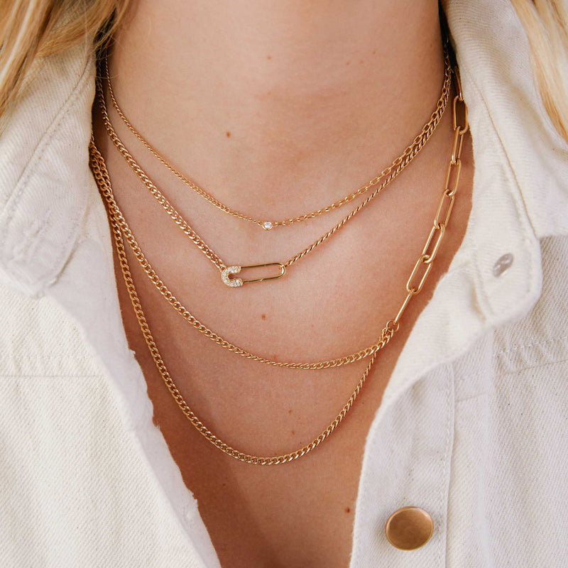 woman in white denim shirt wearing a Zoë Chicco 14k Gold Mixed Paperclip Chain & Draped Double Small Curb Chain Necklace layered with two other heavy chain necklaces
