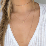 woman in white top wearing Zoë Chicco 14k Gold Initial Shield Necklace
