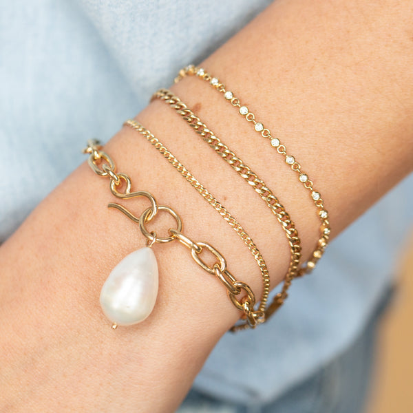 woman's wrist wearing a Zoë Chicco 14k Gold Extra Small Curb Chain Bracelet layered with a Small Curb Chain Bracelet