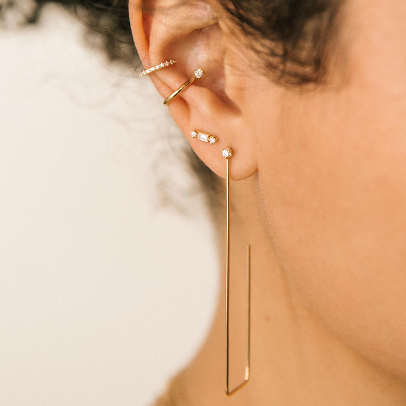 close up of woman's ear wearing Zoë Chicco 14k Gold Baguette & 2 Prong Diamond Stud Earrings with a Prong Diamond Ear Cuff and Pave Diamond Ear Cuff