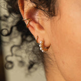 close up of woman's ear wearing a Zoe Chicco 14k Gold Thick Open Ear Cuff with an XS Hinge Huggie Hoop Earring and a Pearl Hinge Huggie Hoop