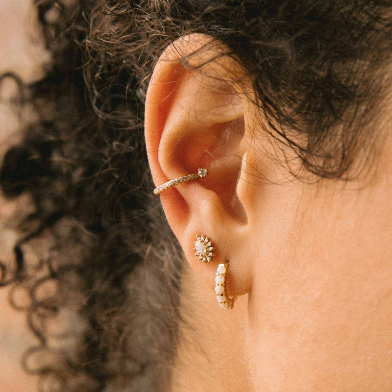 close up of woman's ear wearing Zoë Chicco 14k Gold Prong Set Opal Small Hinge Huggie Hoop Earring with an Opal Marquise Cluster Stud and Pave Diamond Prong Diamond Ear Cuff