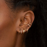 woman's ear wearing Zoë Chicco 14k Gold Mixed Wire Pave Diamond Double Ear Cuff layered with plain gold huggie hoops