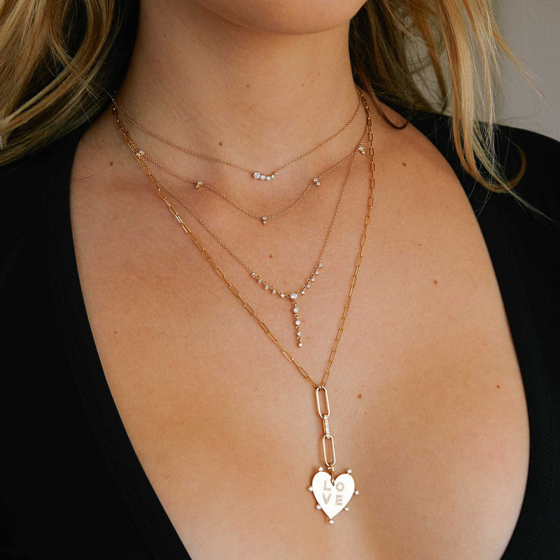 woman in black top wearing a long paperclip chain necklace with a lariat drop that has a Zoë Chicco 14k Gold 7 Prong Diamond Pavé Diamond LOVE Heart Clip on Charm Pendant clipped at the bottom