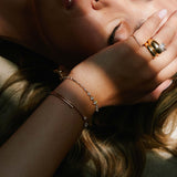Woman wearing a Zoë Chicco 14k Gold Linked Graduated Prong Diamond Tennis Bracelet on her wrist holding her hand up to her face while lying on the ground