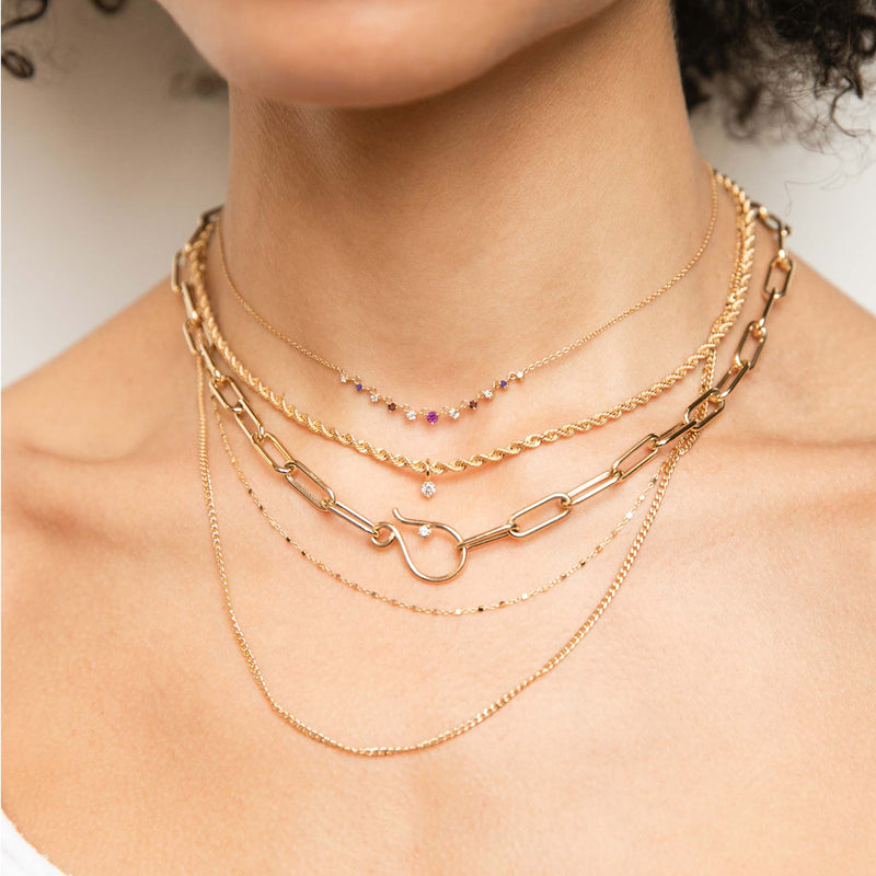 a woman wearing a Zoë Chicco 14k Gold Linked Graduated Pink Ombre Gemstone Necklace layered with multiple other necklaces