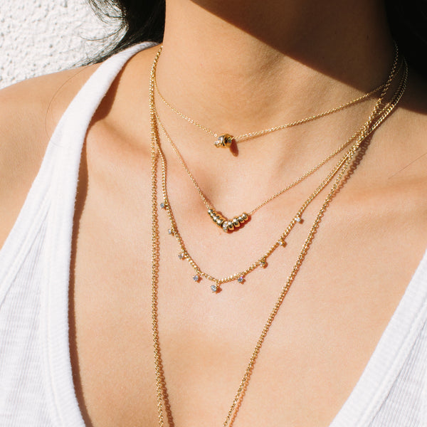 woman wearing Zoë Chicco 14kt Gold 9 Graduated Rondelle Pavé Diamond Necklace layered with three other necklaces