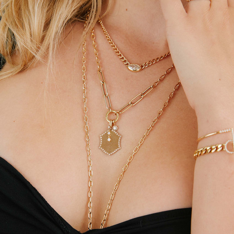 a woman in a black top wearing a Zoë Chicco 14k Gold Diamond Hexagon Charm Pendant hanging from a heavy chain necklace