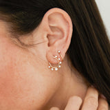 close up of woman's ear wearing a Zoë Chicco 14k Gold Graduated Prong Diamond Front to Back Circle Hoop Earring layered with a Thick Huggie Hoop with Prong Diamond in her second piercing