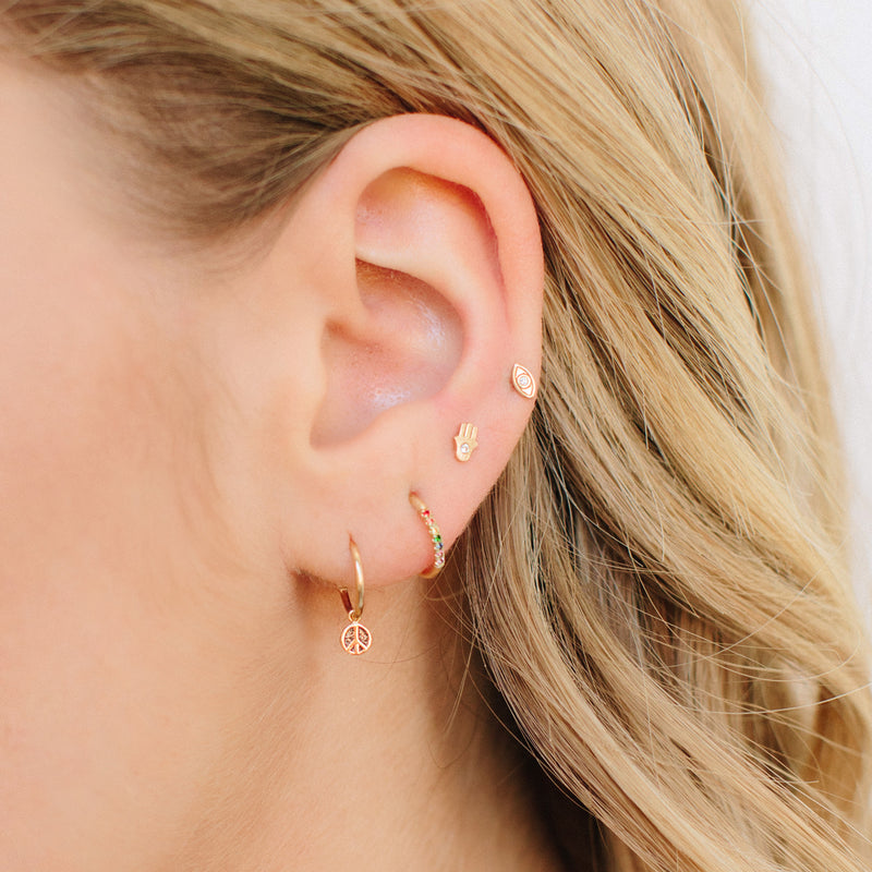 woman wearing a Zoë Chicco 14k Gold Itty Bitty Diamond Evil Eye Stud Earring in her fourth piercing layered with other itty bitty earrings