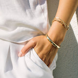 close up of woman wearing all white with her hand in pocket wearing Zoë Chicco 14kt Gold Half Round Star Set Graduated Diamonds Cuff on her wrist