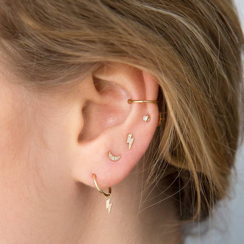 woman's ear wearing a Zoë Chicco 14k Gold Pavé Diamond Lightning Bolt Stud Earring with a Crescent Moon Stud Earring