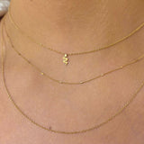 woman wearing Zoe Chicco 14k Gold Itty Bitty Snake Necklace layered with a Tiny Bar and Cable & Cable Chain Layered Necklace