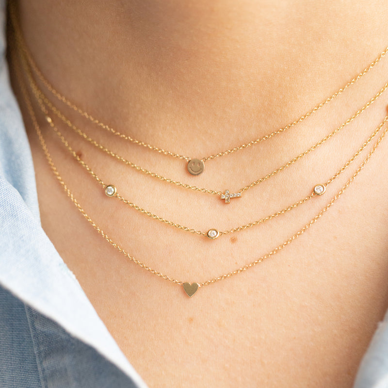 woman wearing Zoë Chicco 14kt Gold Itty Bitty Heart Necklace layered with three other itty bitty necklaces