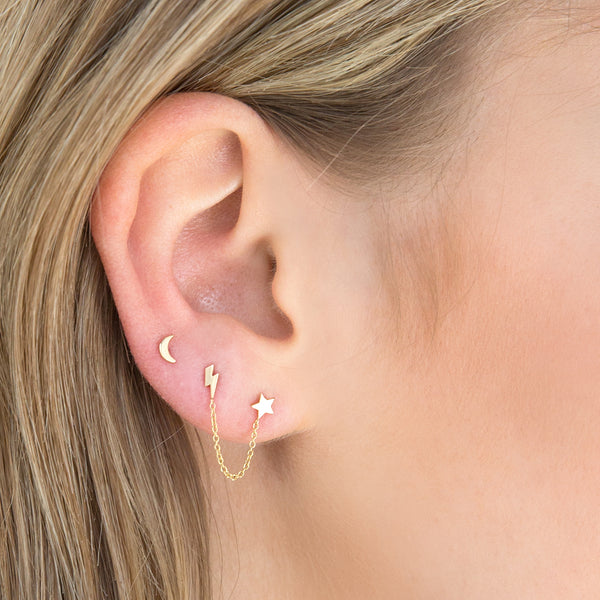 close up of woman's ear wearing a Zoë Chicco 14k Gold Itty Bitty Crescent Moon Stud Earring with a Itty Bitty Lightning Bolt & Star Chain Double Stud