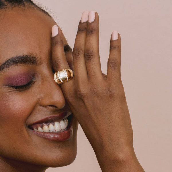 woman smiling with eyes closed and holding her hand up to her eye wearing Zoë Chicco 14k Gold Pavé Diamond Banded Large Aura Ring on her index finger