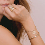 woman with hand resting on chin and wearing Zoë Chicco 14k Gold Diamond Evil Eye Medallion Square Oval Link Bracelet on her wrist