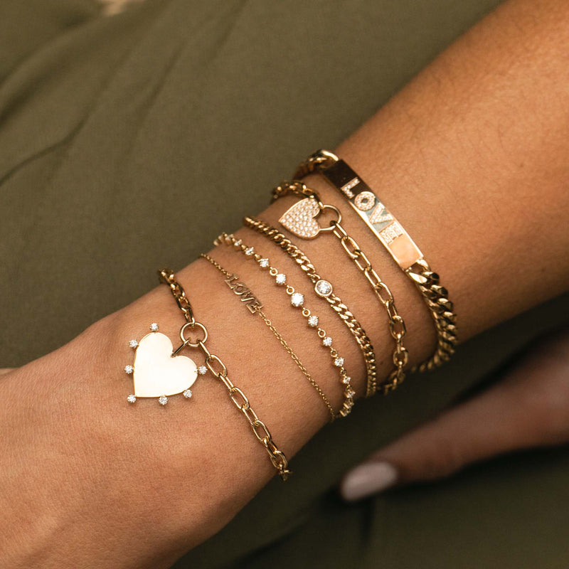 woman's wrist wearing Zoë Chicco 14k Gold Graduated Linked Prong Diamond Bolo Bracelet stacked with other bracelets