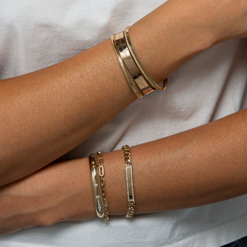 woman in white t-shirt wearing Zoë Chicco 14k Gold Medium Square Oval Link Bracelet with 5 Pavé Diamond Links on her wrist