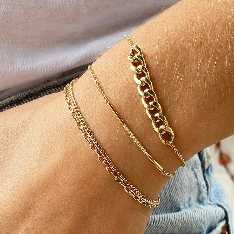 wrist wearing Zoe Chicco 14kt Gold XS Curb & Small Oval Link Double Chain Bracelet and two other chain bracelets