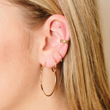 woman's ear wearing a Zoë Chicco 14k Gold 3 Bead Set Diamond Huggie Hoop Earring layered with two other bead set diamond hoops