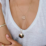 woman in a white v neck tshirt wearing a Zoë Chicco 14k Gold Star Set Diamond Round Locket Necklace with Floating Diamond layered with a sunbeam medallion necklace