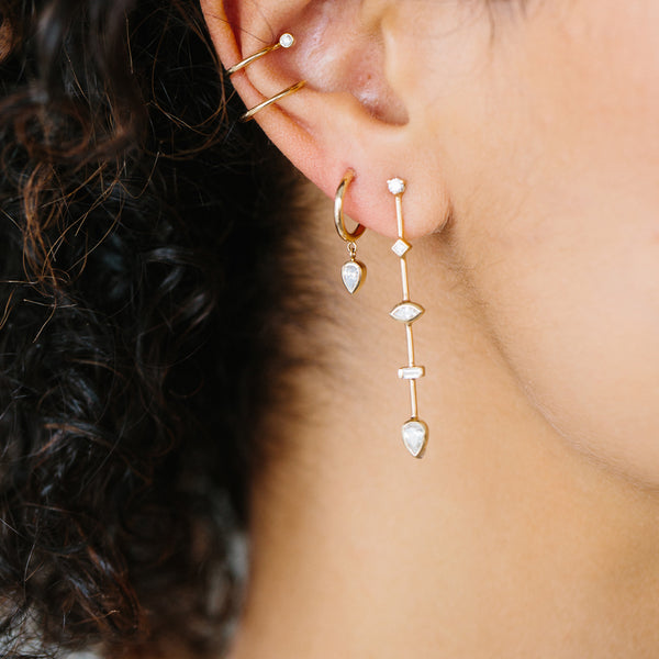 woman wearing Zoë Chicco 14kt Gold Thick Huggie Hoops with Dangling Pear Diamonds