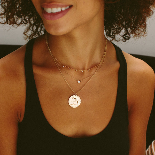 woman in black tank top wearing Zoë Chicco 14kt Gold Single Large Mantra Medallion Disc Charm Pendant engraved with I "heart" you to the "moon" and back on a cable chain necklace